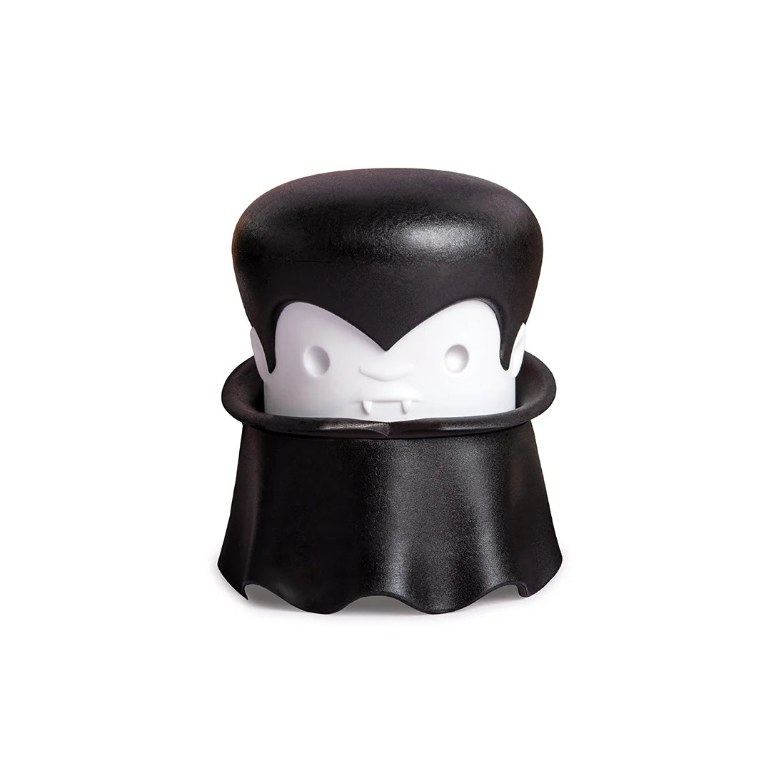 A cartoon vampire with a cape and fangs holds an OTOTO Gracula garlic crusher.