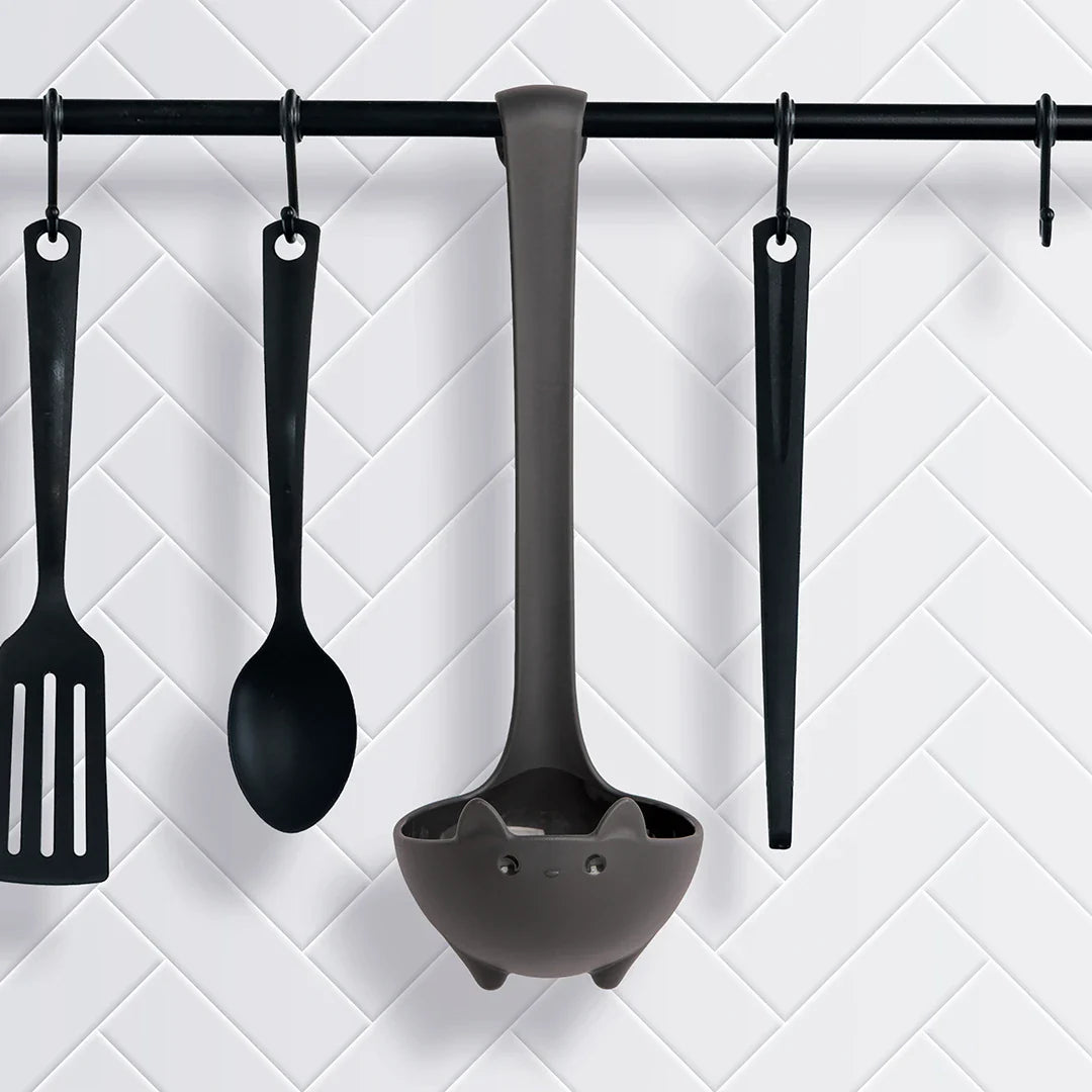 OTOTOs Katie soup ladle, spatula, spoon, and tongs hang on hooks against a white tiled wall.