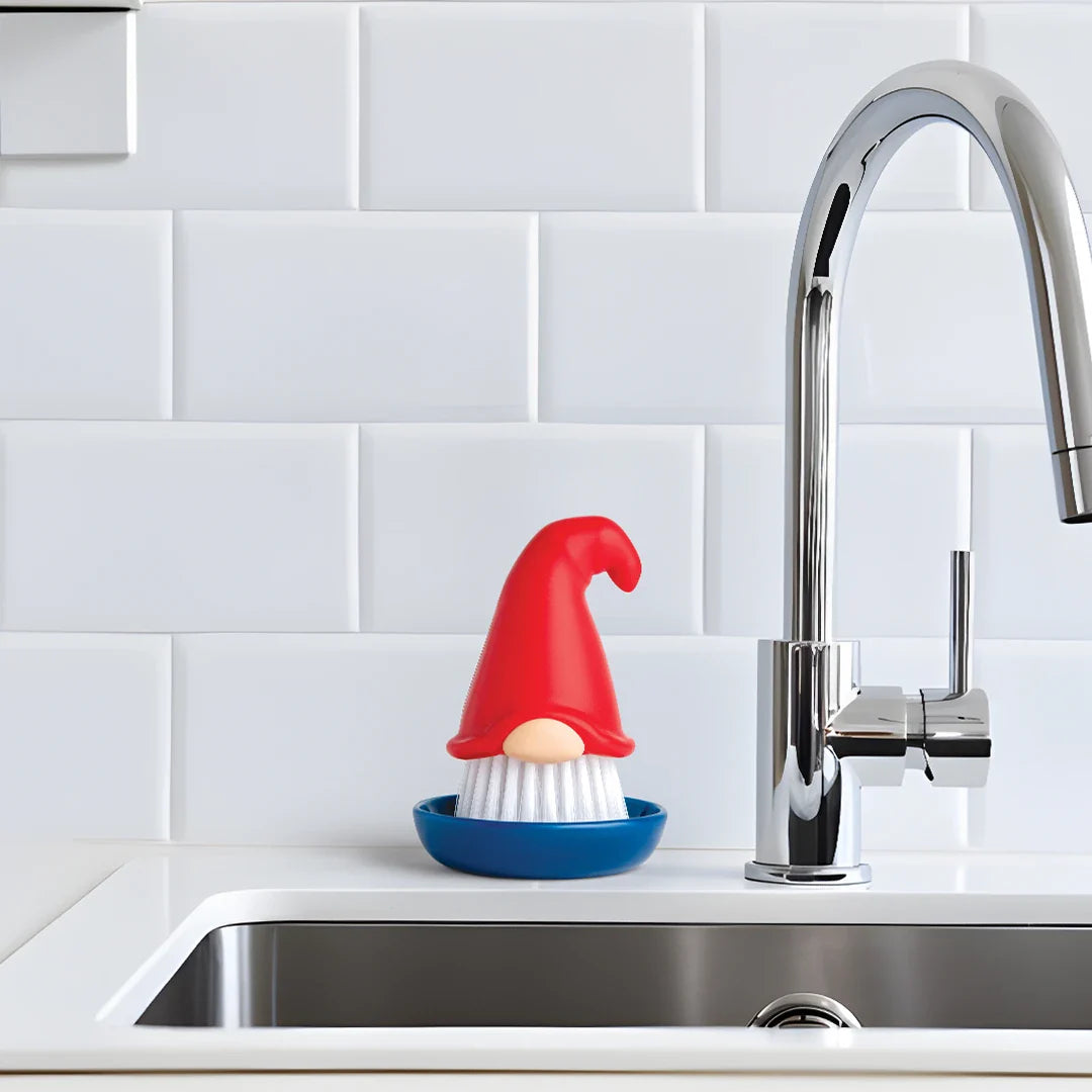 OTOTOs Beardy dish brush adds fun to kitchen chores by the sink with a white tiled backsplash.