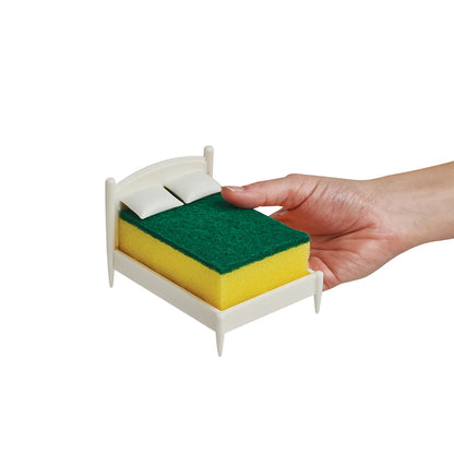 A hand holds Clean Dreams, a whimsical holder with a tiny bed and two mini pillows.