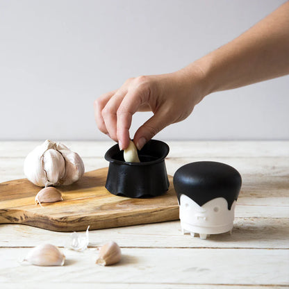 Hand using the Gracula on a wooden board with garlic bulbs.