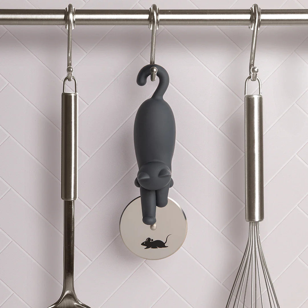 The OTOTO Kitty-Cut pizza cutter hangs on a rod, surrounded by kitchen utensils.