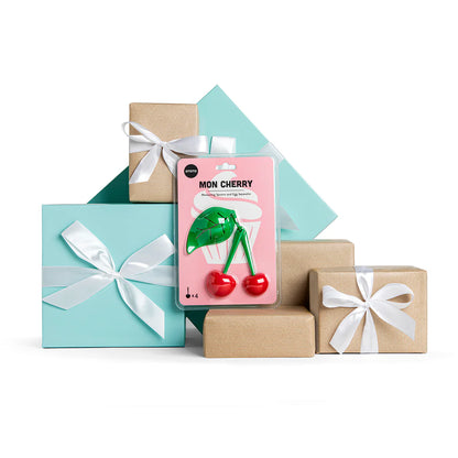 Mon Cherry gift boxes with white bows and a cherry-shaped corkscrew plus measuring spoons on white.