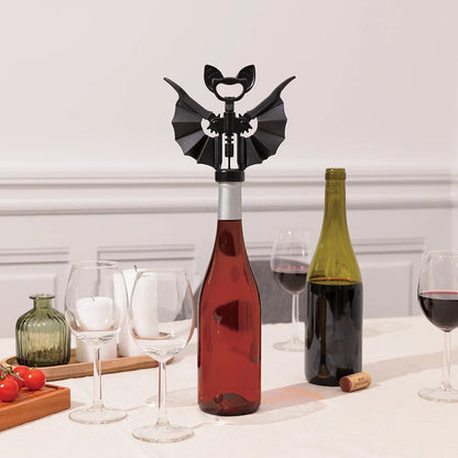 OTOTO Vino corkscrew shaped like a bat on a wine bottle, surrounded by glasses and another bottle.