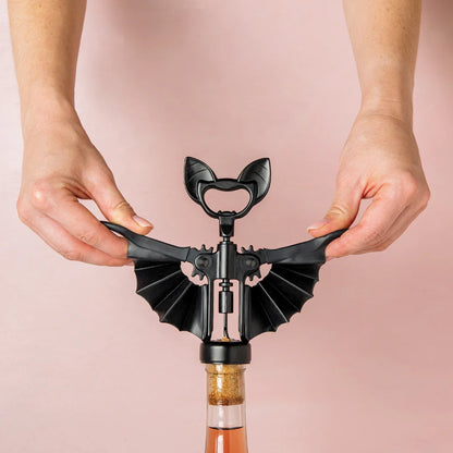 A person uses a Vino bat-shaped corkscrew by OTOTO to open a wine bottle.